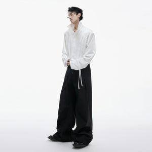 Model wearing brown oversized pleated shirt with metallic streamers