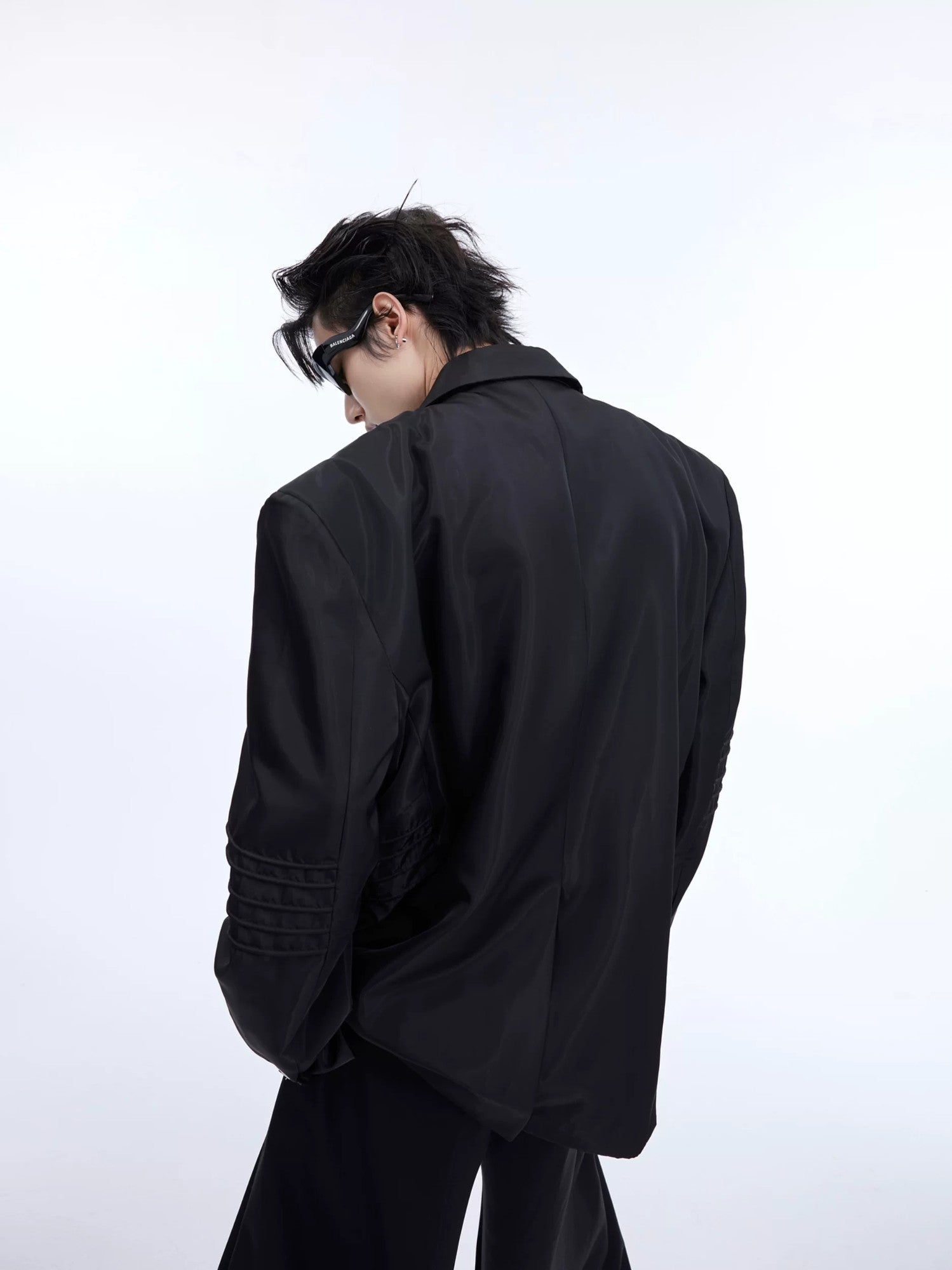 Close-up of deconstructed pleats and metallic texture on a black blazer