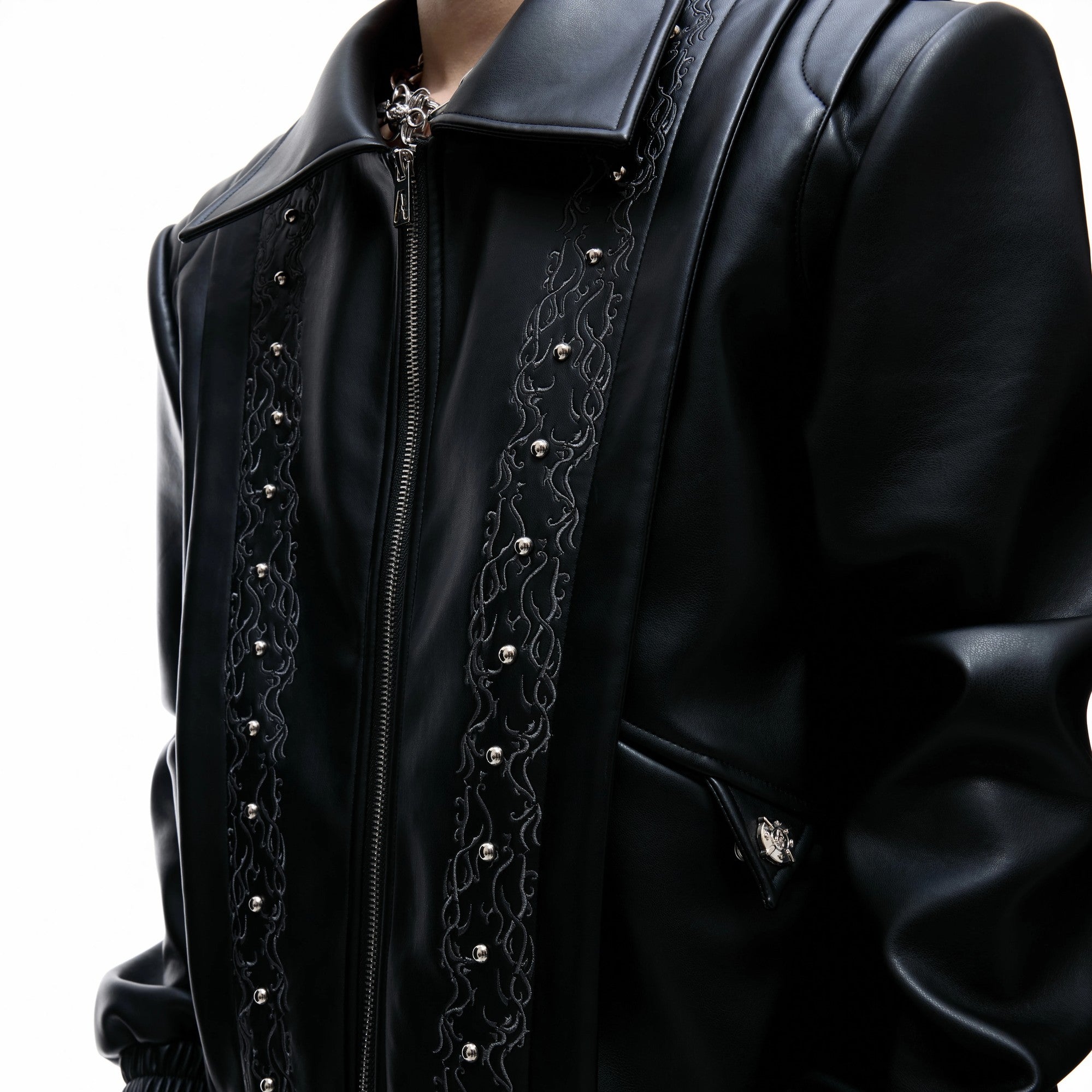 Close up of intricate vine embroidery and metallic studs on leather jacket