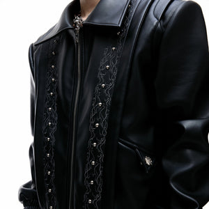 Close up of intricate vine embroidery and metallic studs on leather jacket
