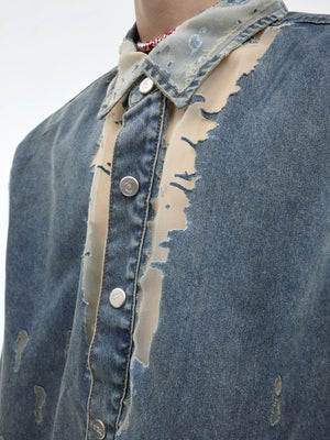 Back view of the distressed denim shirt showing the rounded hem and loose fit.