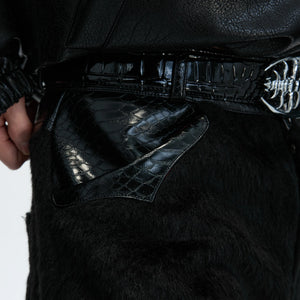 Wide-leg flared silhouette of the black patchwork pants styled with boots.