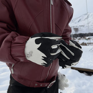 Detail view of the metal brand tag and deconstructed stitching on leather gloves