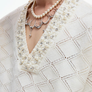 Model wearing a gray argyle knit sweater in a street setting