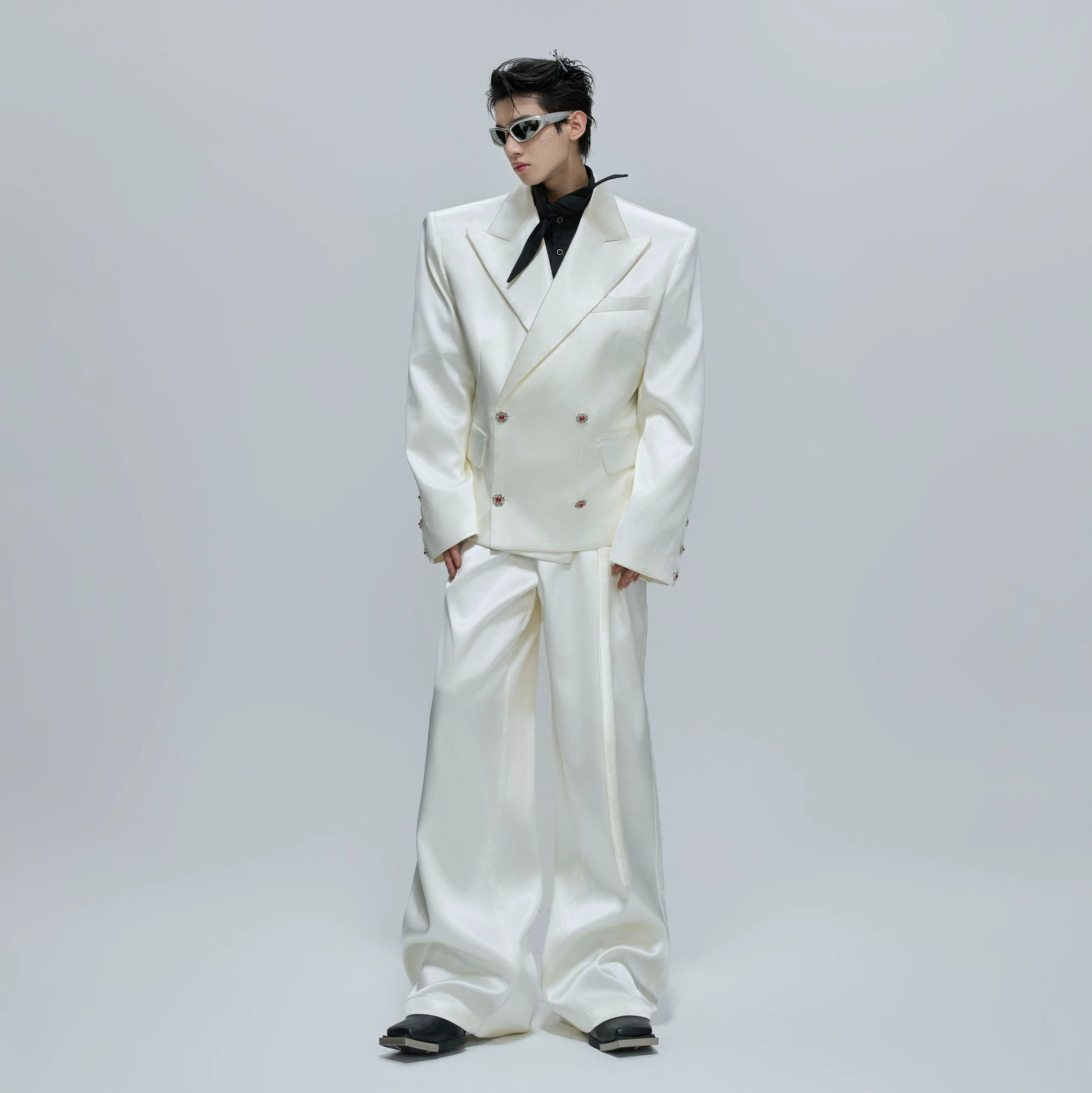 Man wearing a black liquid gloss oversized suit jacket and flared pants