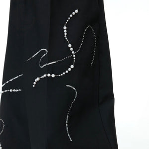 Close-up of unique beaded waistband detailing on loose streetwear trousers with snake year design