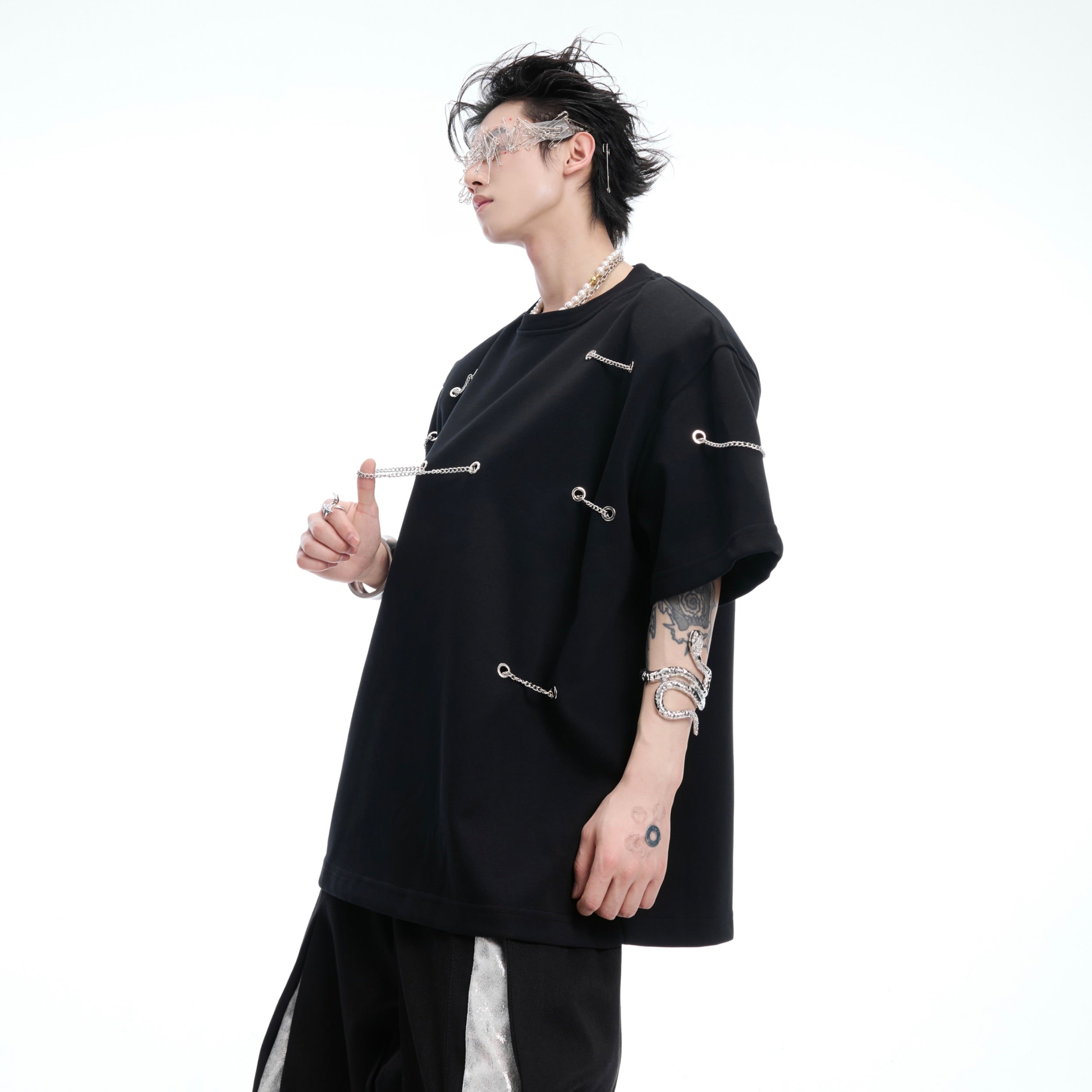 Side angle showing deconstructed chain patchwork detail on black cotton t-shirt with urban edge design