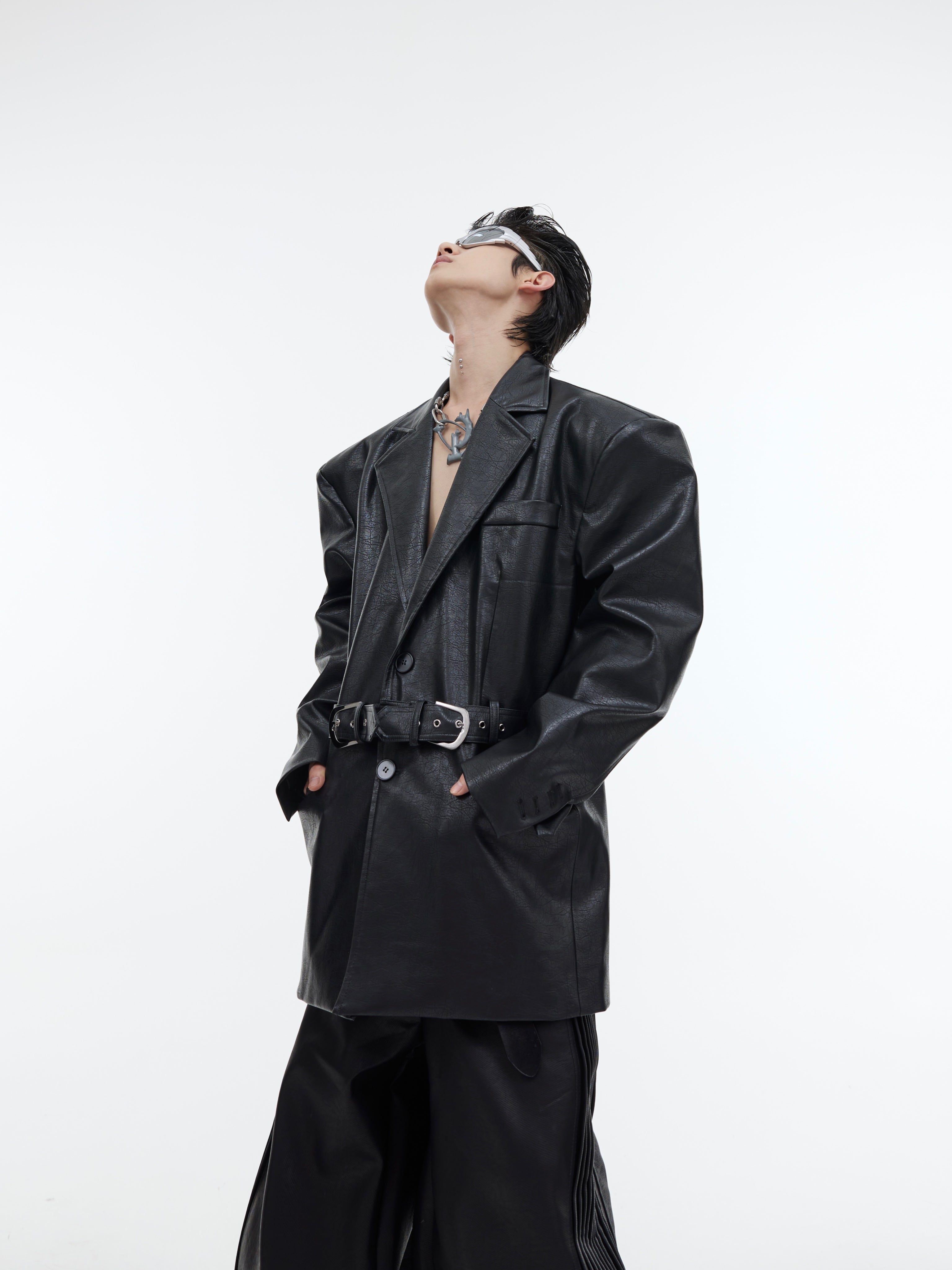 Front view of oversized leather blazer with deconstructed belt detail showing urban streetwear aesthetic