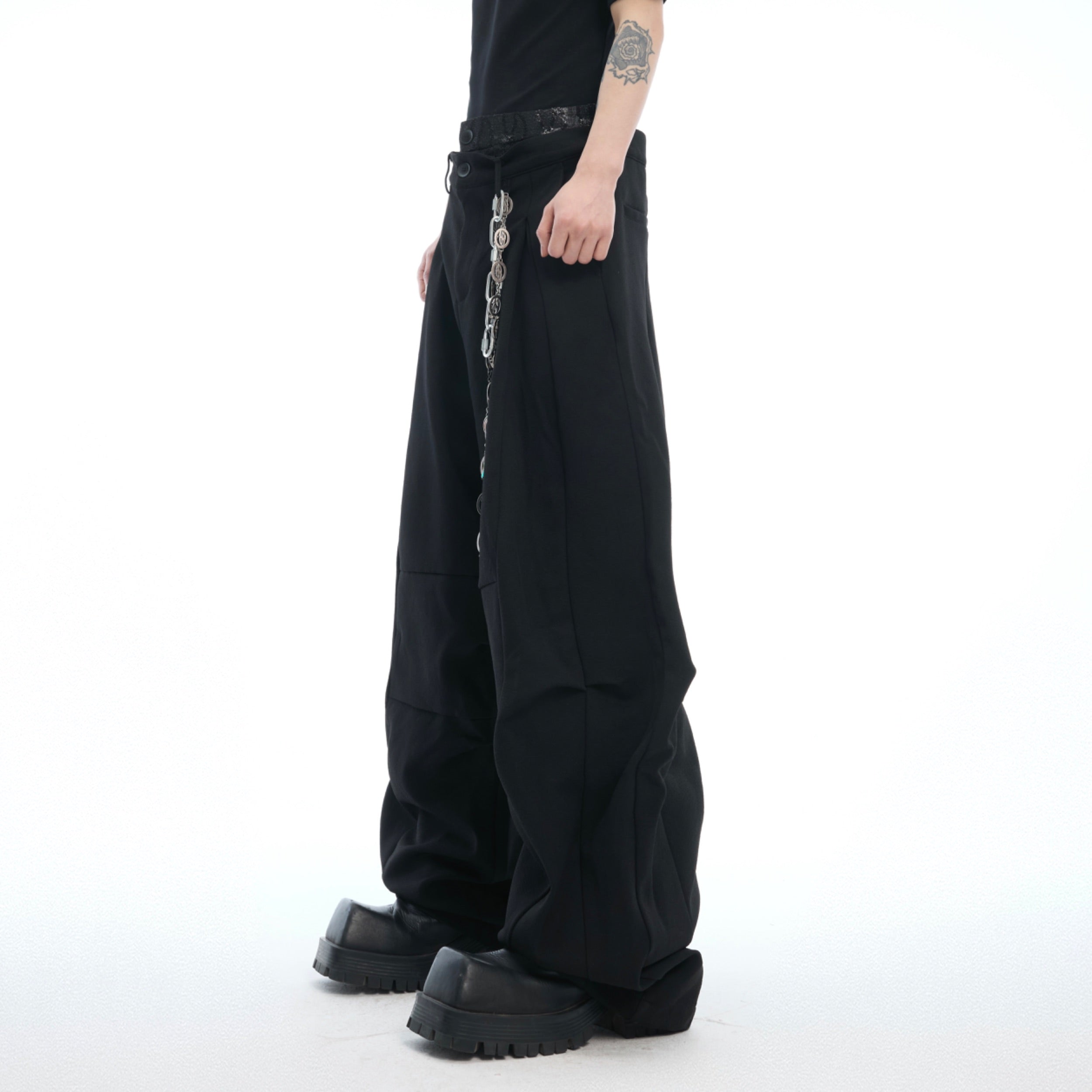 Front view of deconstructed drop-crotch trousers showing unique layered waist design in streetwear style