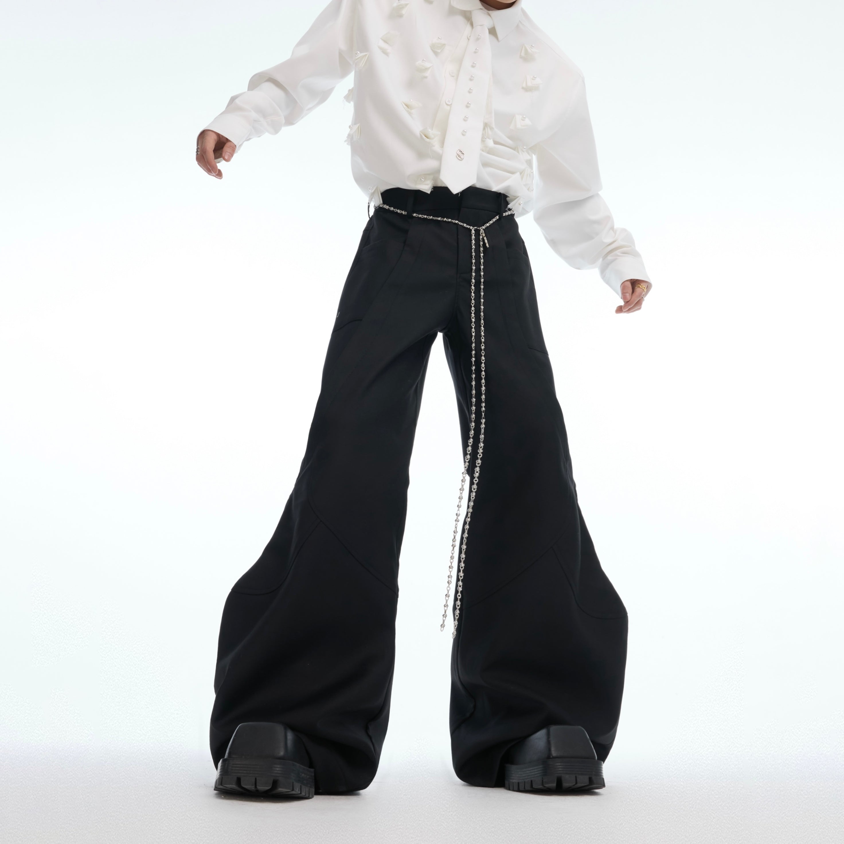 Front view of streetwear deconstructed flared pants with edgy metal chain detailing and micro-rips