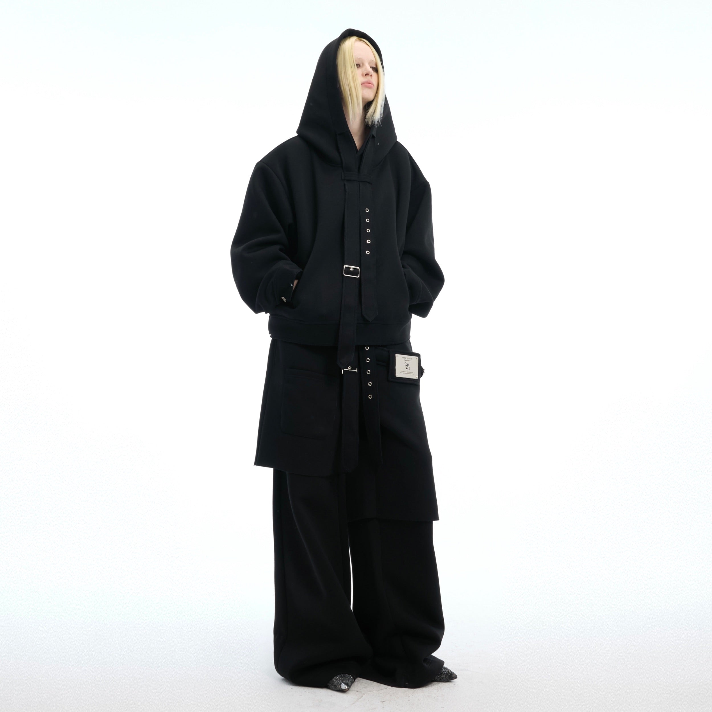 Front view of oversized deconstructed hoodie with detachable sash, showcasing urban streetwear style with metal accents