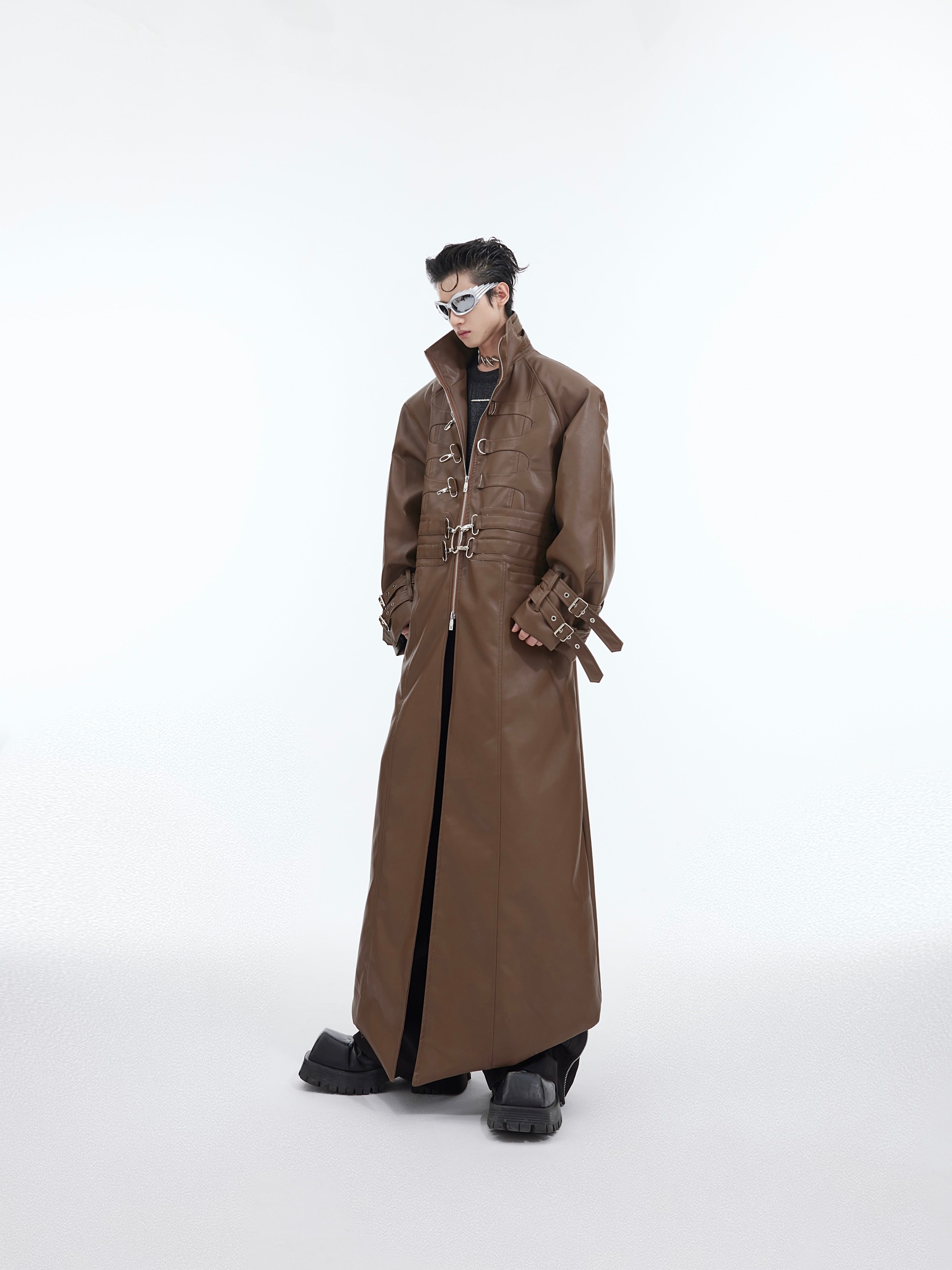 Deconstructed leather trench coat with silver metal buckles, showing front view of this avant-garde streetwear jacket
