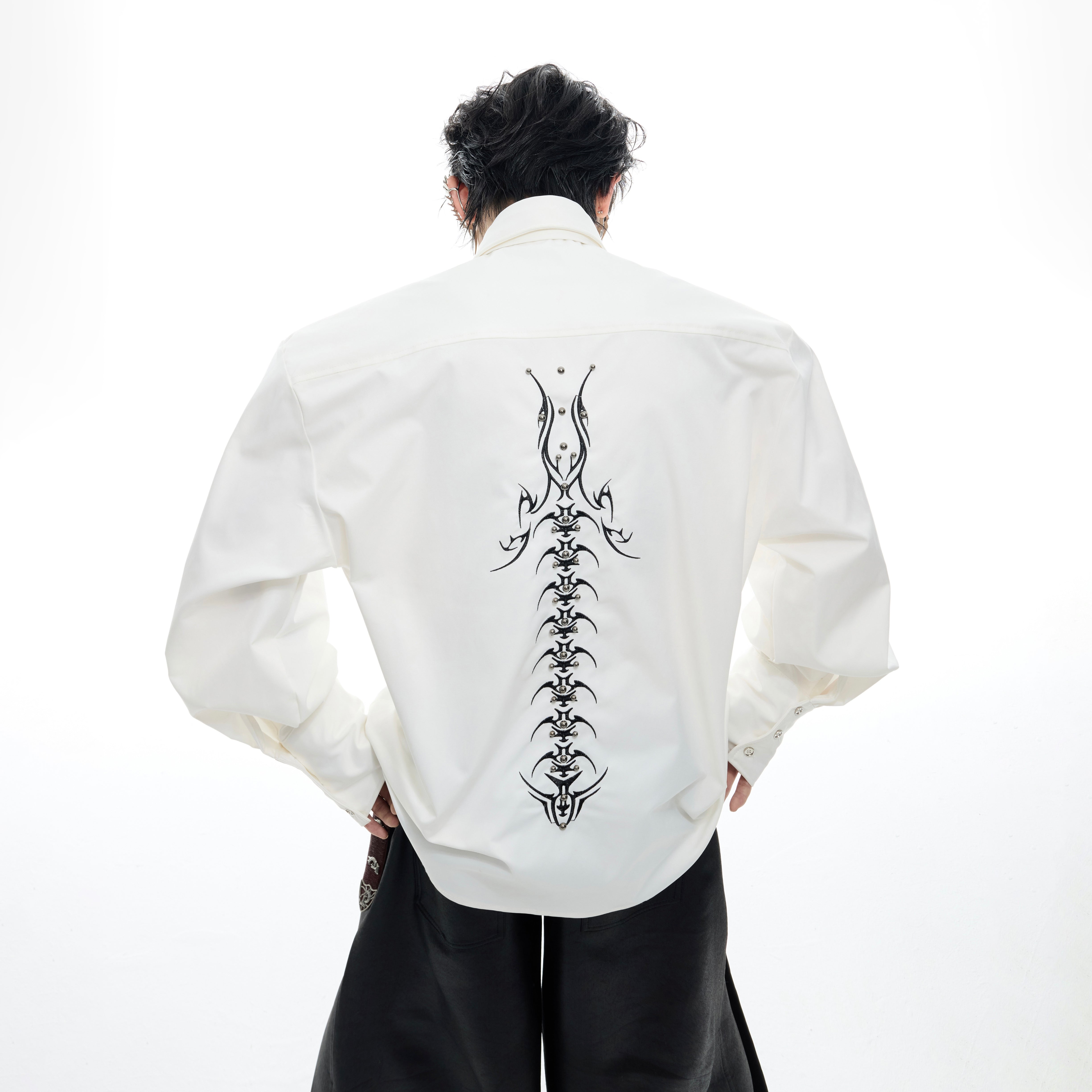Front view of deconstructed spine-embroidered shirt showing avant-garde streetwear design with loose fit
