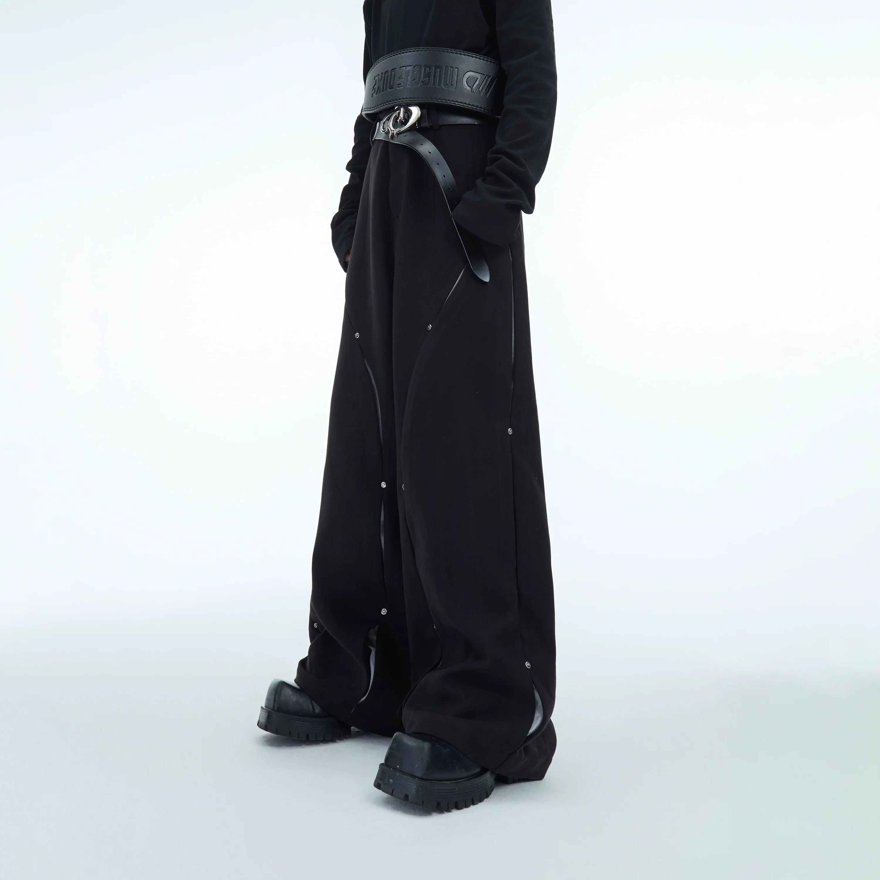 Front view of loose fit deconstructed wool pants with silver metal studs, showcasing urban streetwear style