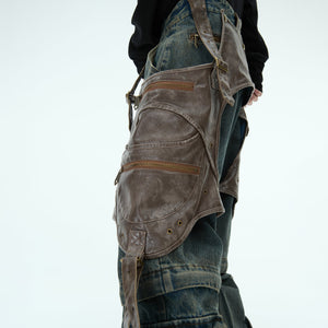 Detail shot showing removable PU saddle straps on deconstructed denim jeans