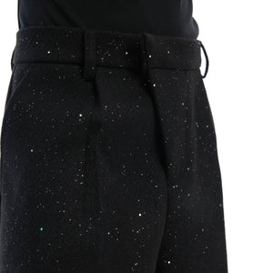 Close-up of the unique slanted waist button on these sparkly wide-leg trousers