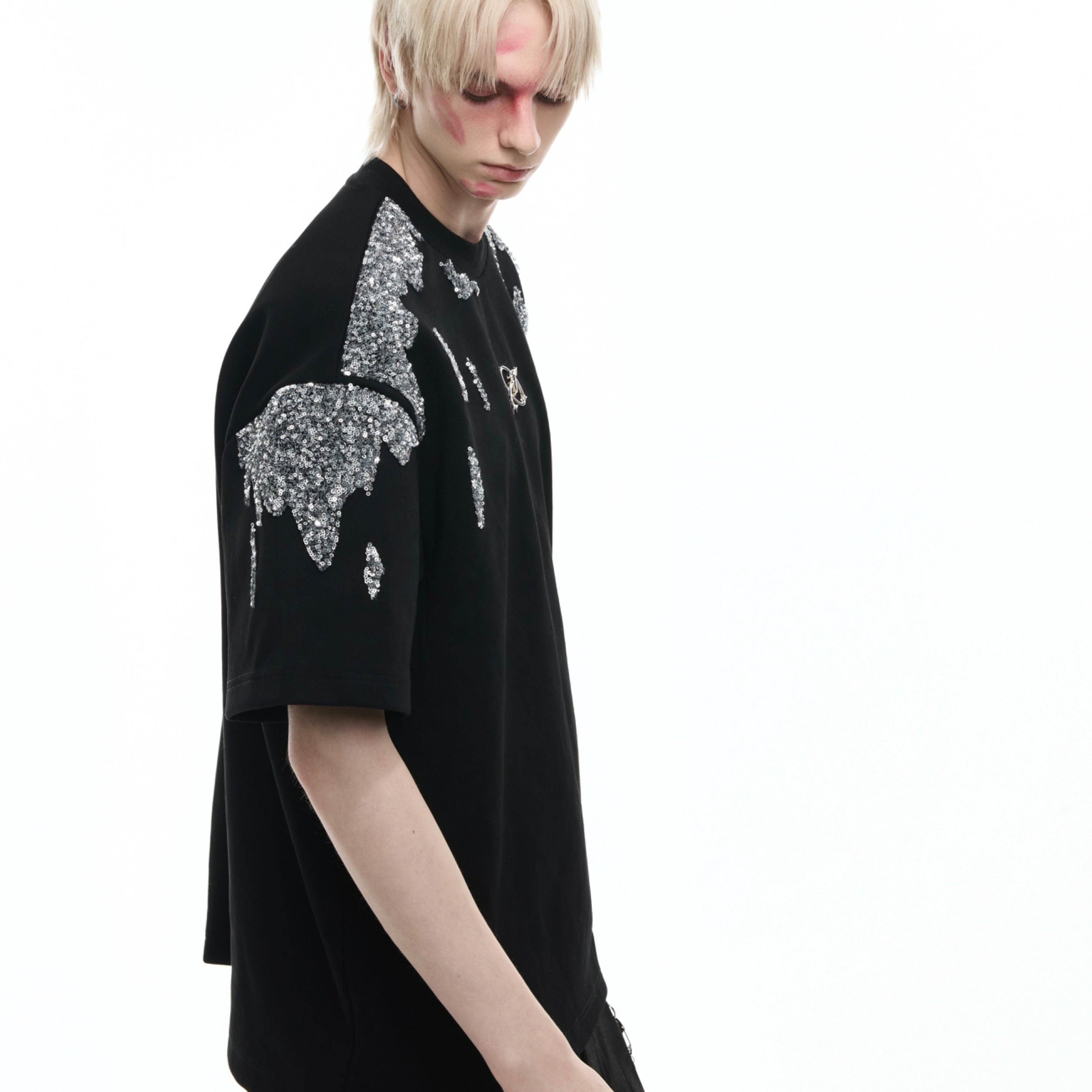 Close-up of asymmetric hem on gold sequin t-shirt showing avant-garde streetwear design