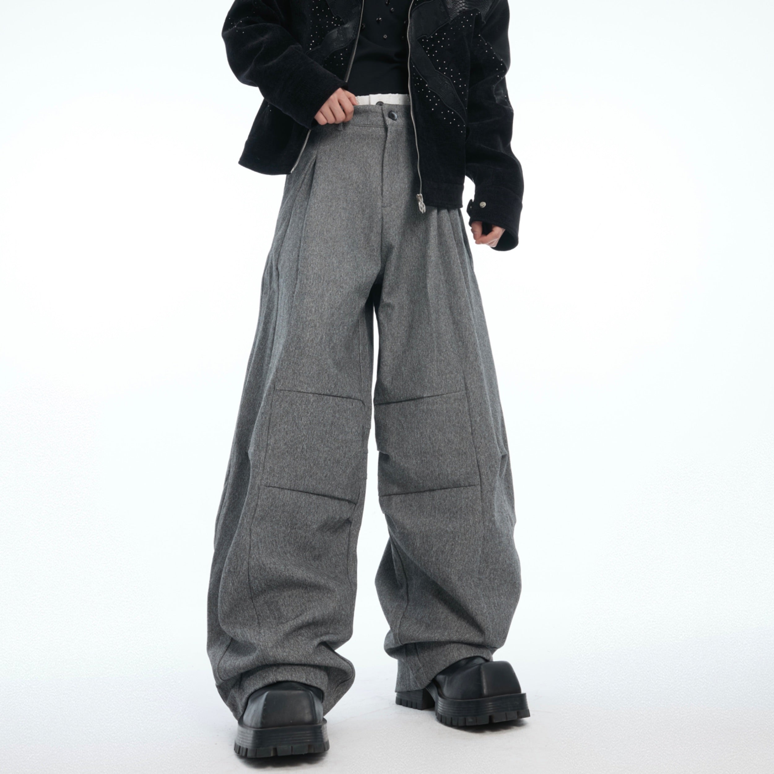 Side angle showing pleated detailing on these avant-garde drop-crotch trousers with loose fit