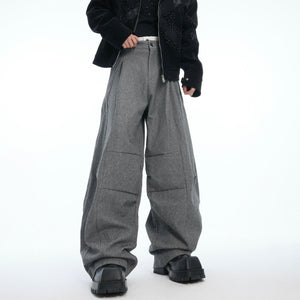 Side angle showing pleated detailing on these avant-garde drop-crotch trousers with loose fit