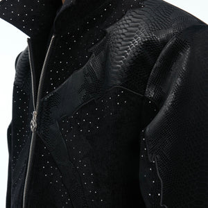 Side profile of edgy croc-embossed bomber jacket with metal rivets and stud details