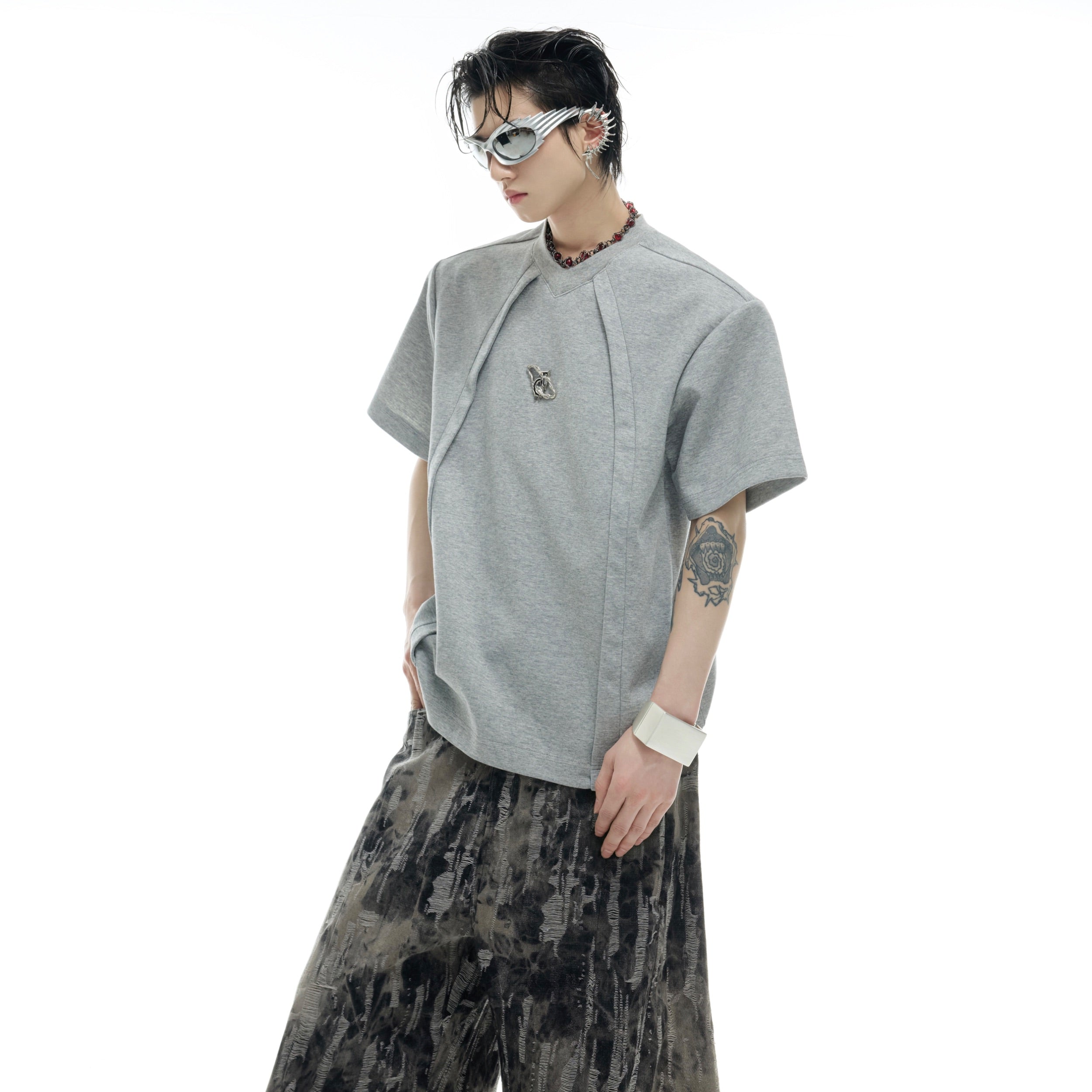 Close-up of raw edge sleeve detailing on premium oversized streetwear t-shirt with metal logo