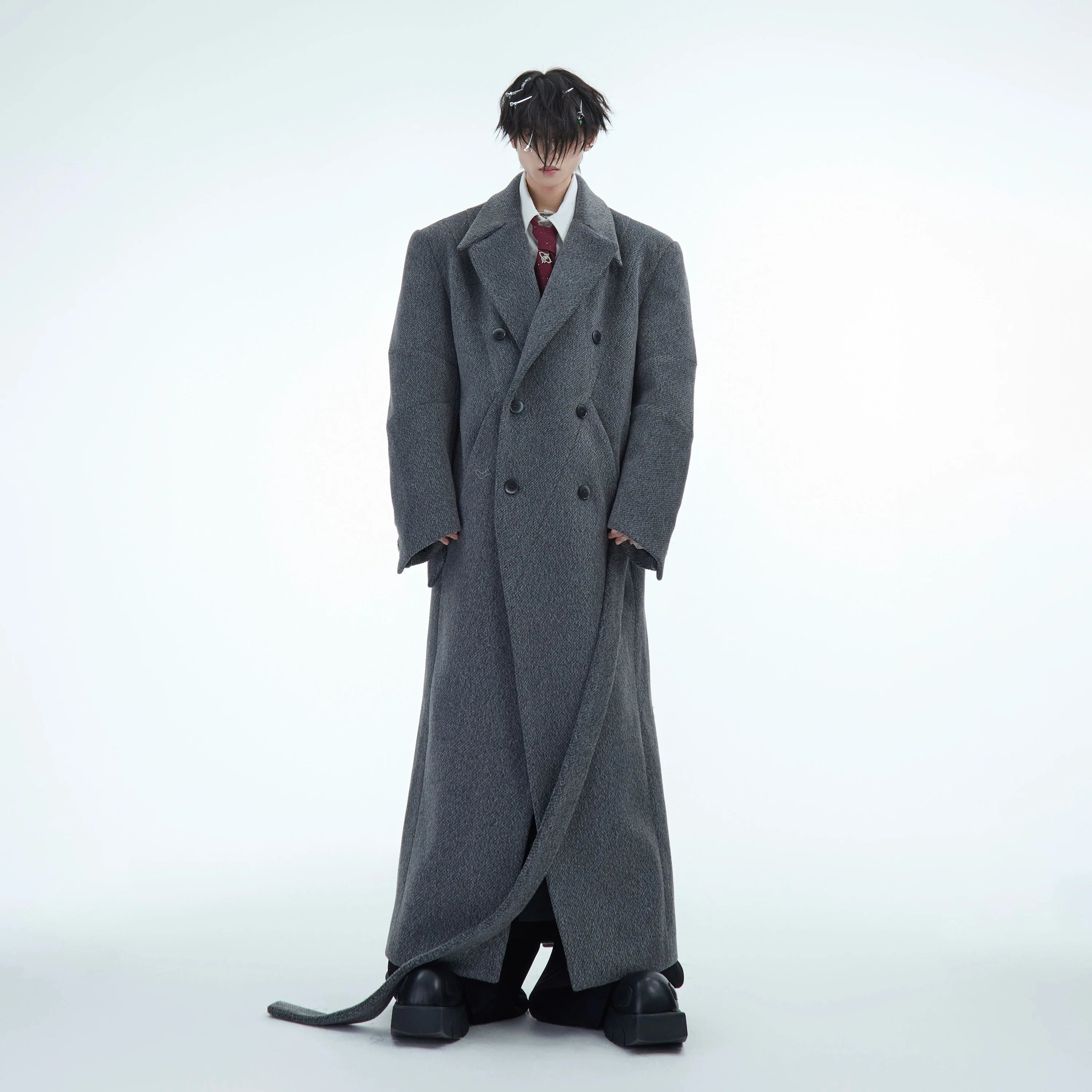 Double-breasted oversized wool trench coat with belted waist, showing the elegant knee-length design and premium fabric texture