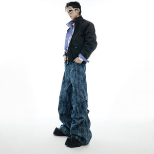 Close-up of distressed jeans showing metallic logo detailing on the textured patchwork denim fabric