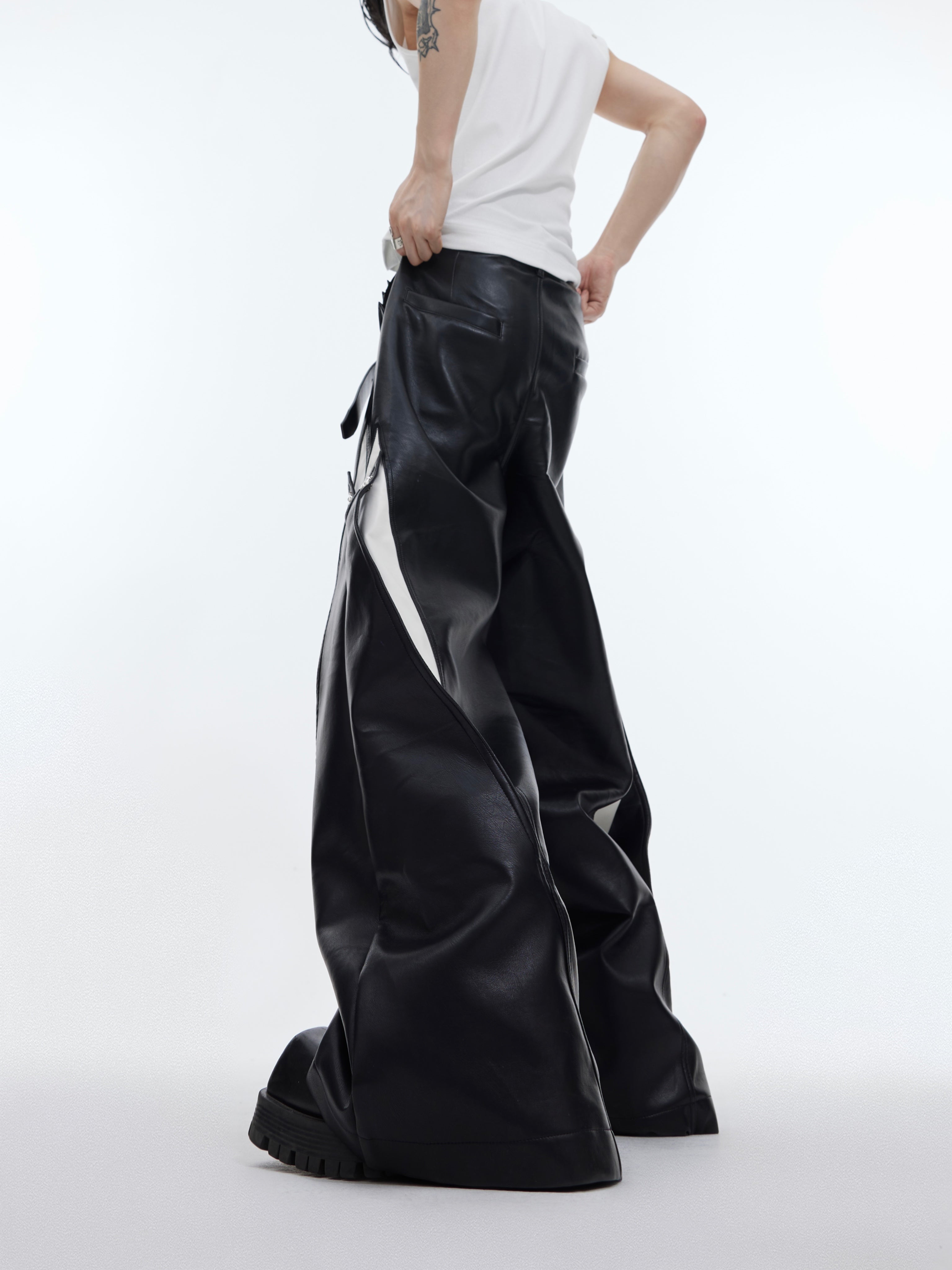 Side angle showing the unique patchwork design and wide leg silhouette of these avant-garde PU pants