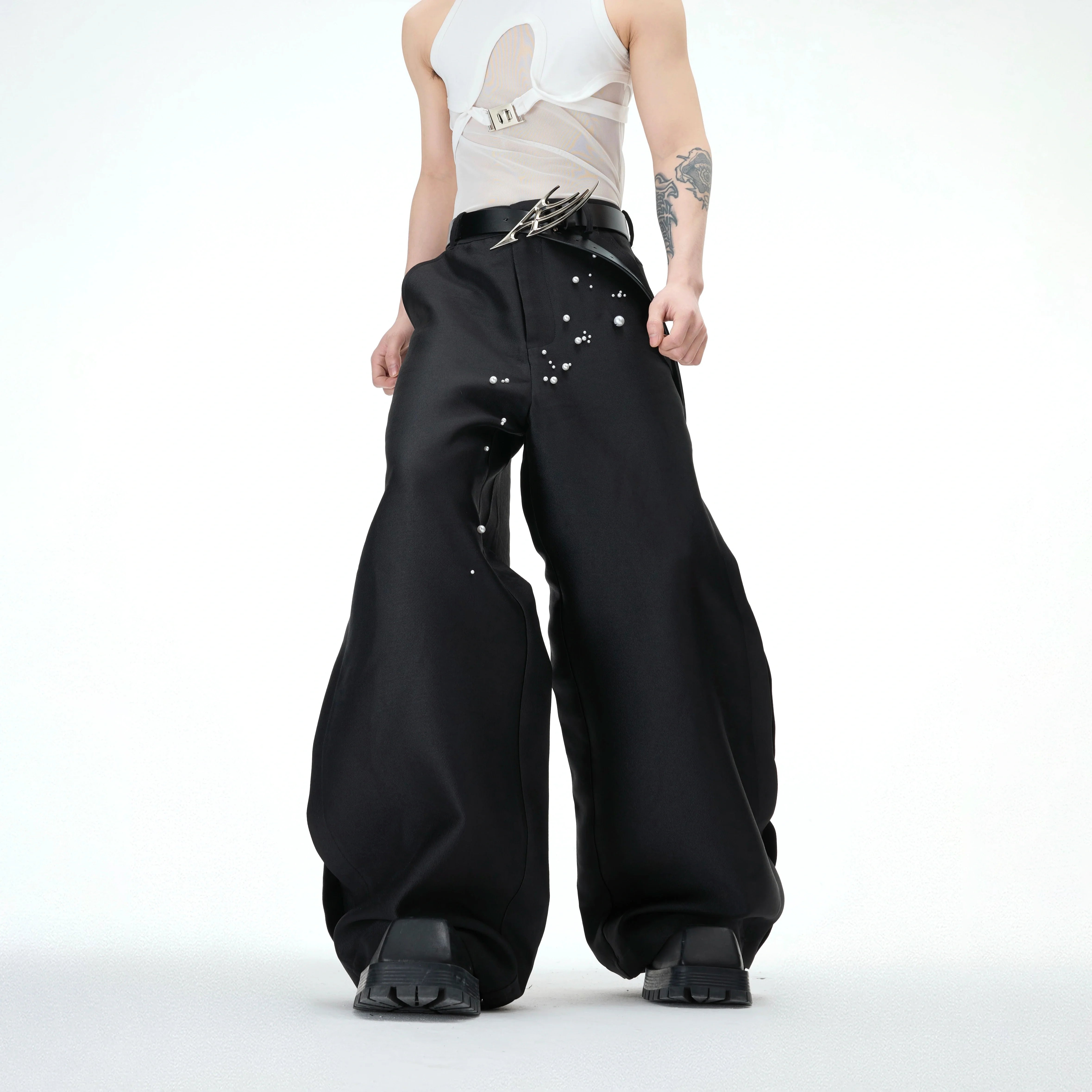 Front view of pearl-embellished waxed wide-leg pants showing streetwear style with gemstone accents