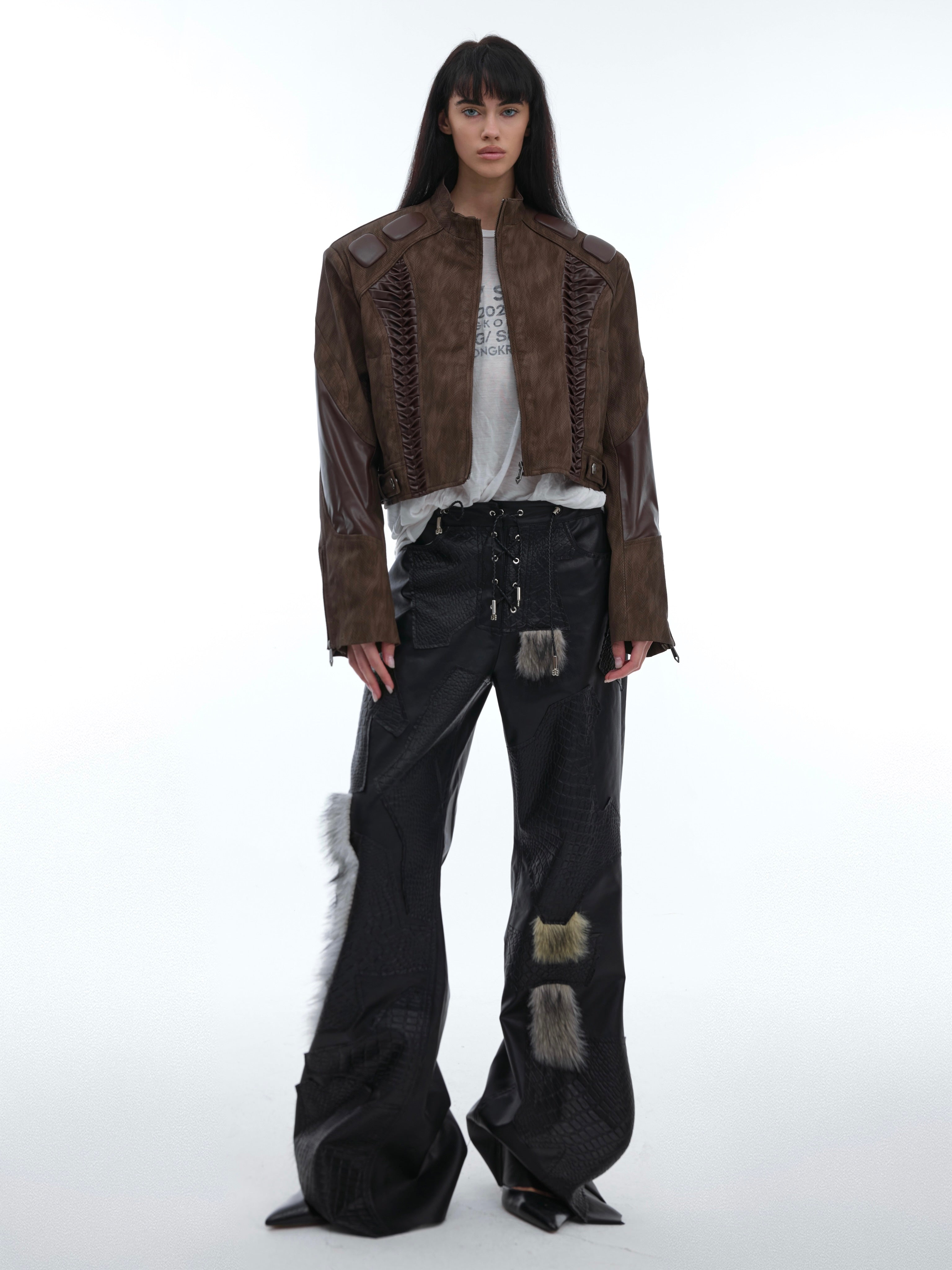Close-up of deconstructed pleated leather pants showing unique cracked texture and punk-inspired tailoring