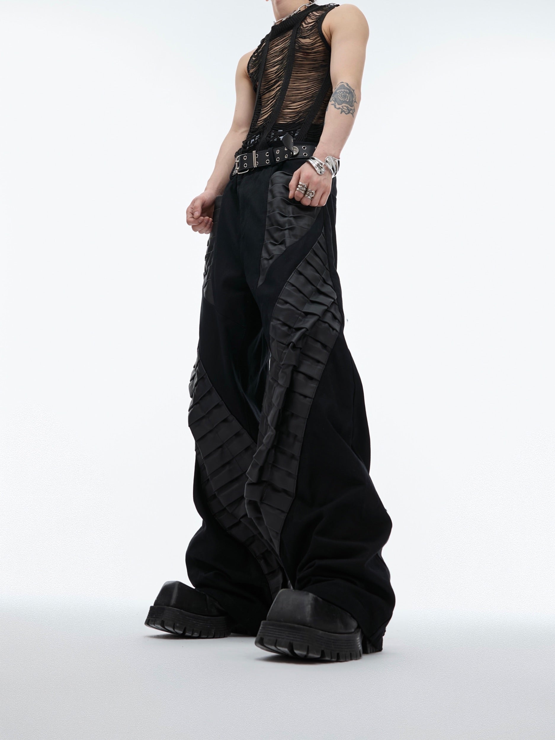 Side profile showing the deconstructed pleated dress pants with unique 3D irregular tailoring and architectural structure