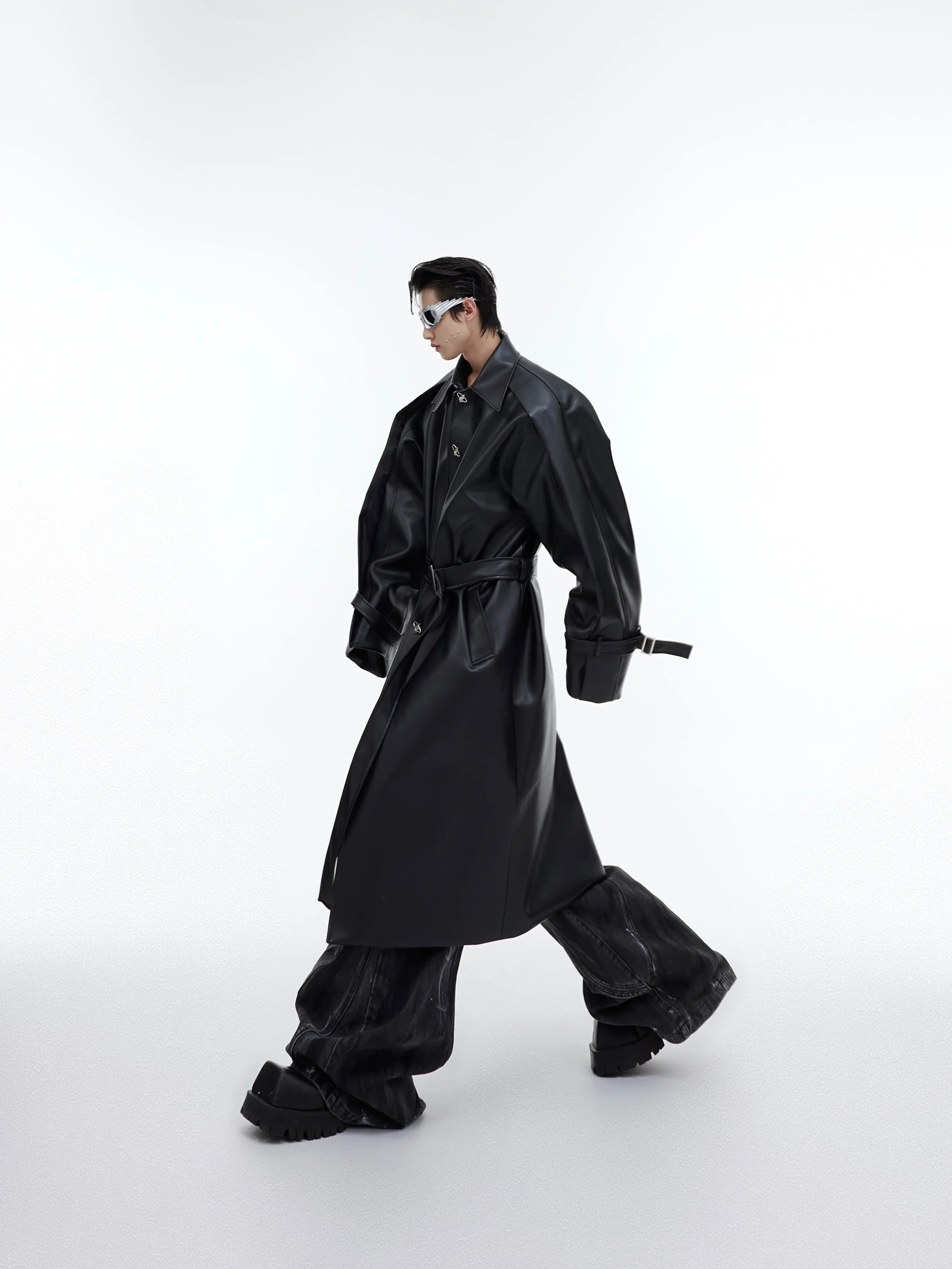 Deconstructed PU leather trench coat with statement metal buttons, showcasing avant-garde streetwear design