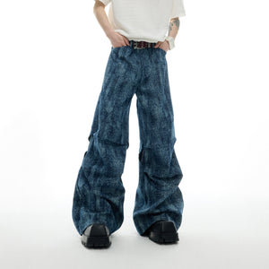 Front view of straight-leg distressed jeans showcasing artful knee rips and patchwork textures