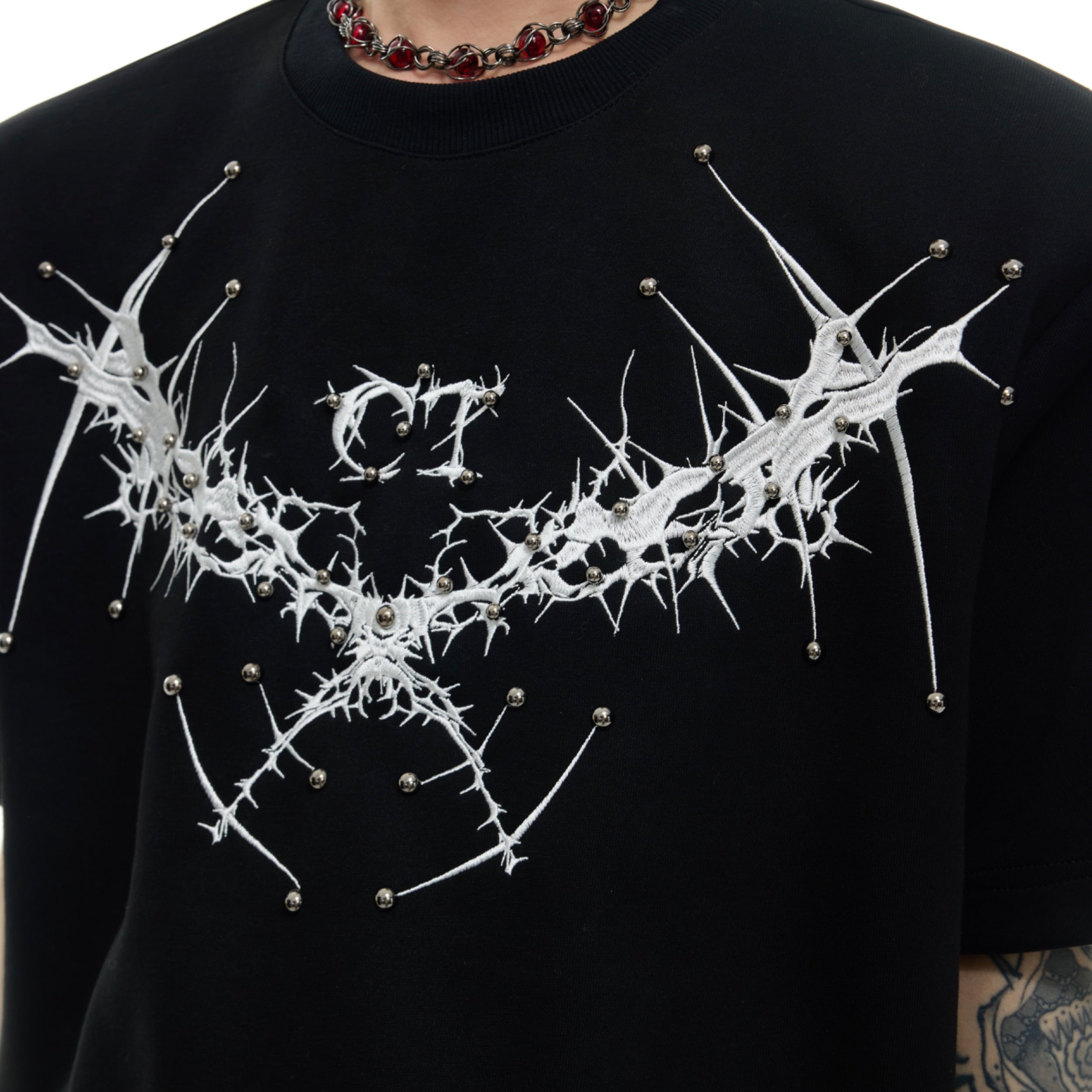 Back view of trendy oversized summer top showing metal rivet embellishments and urban streetwear style