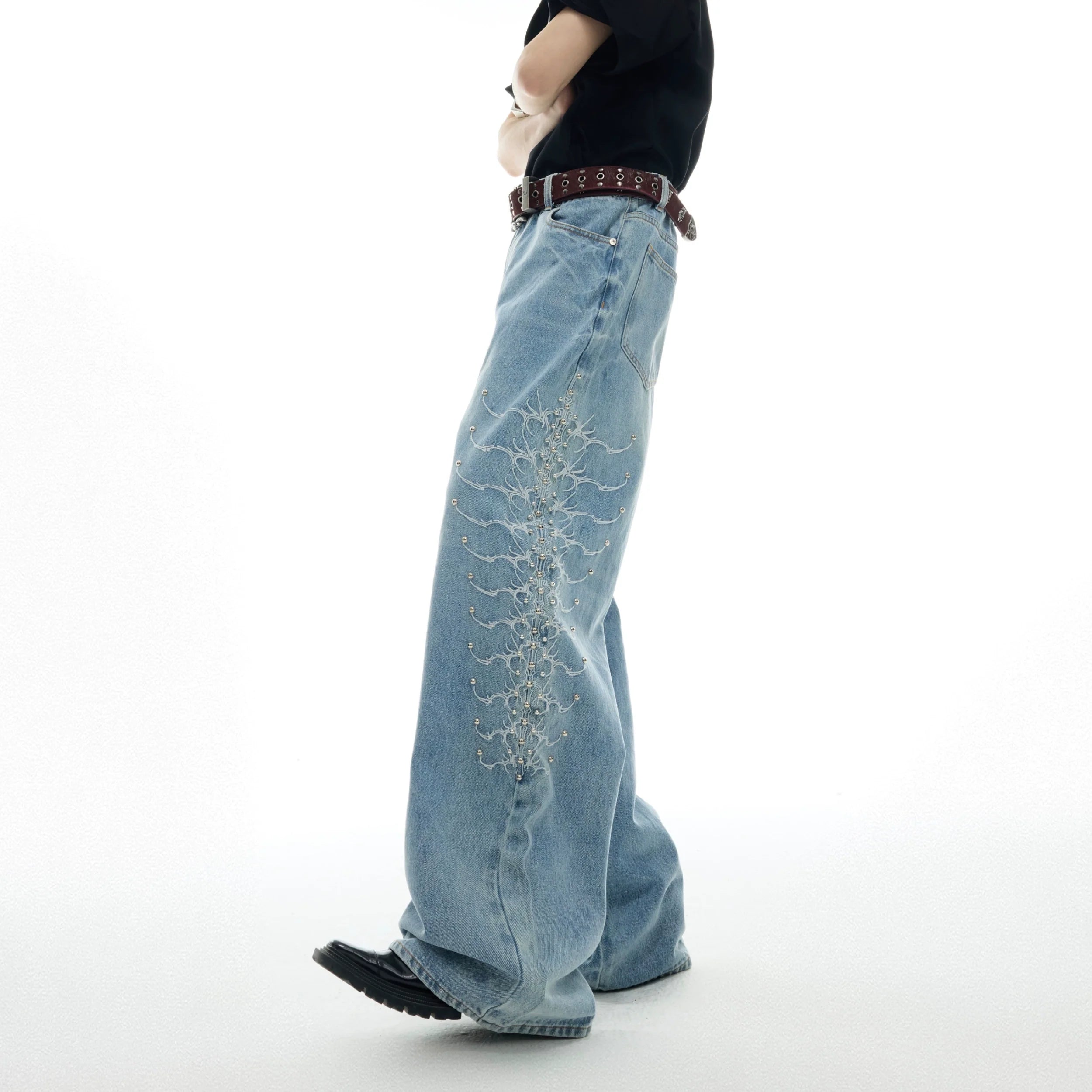 Front view of vintage washed denim jeans featuring unique snake-eye studs and distressed detailing