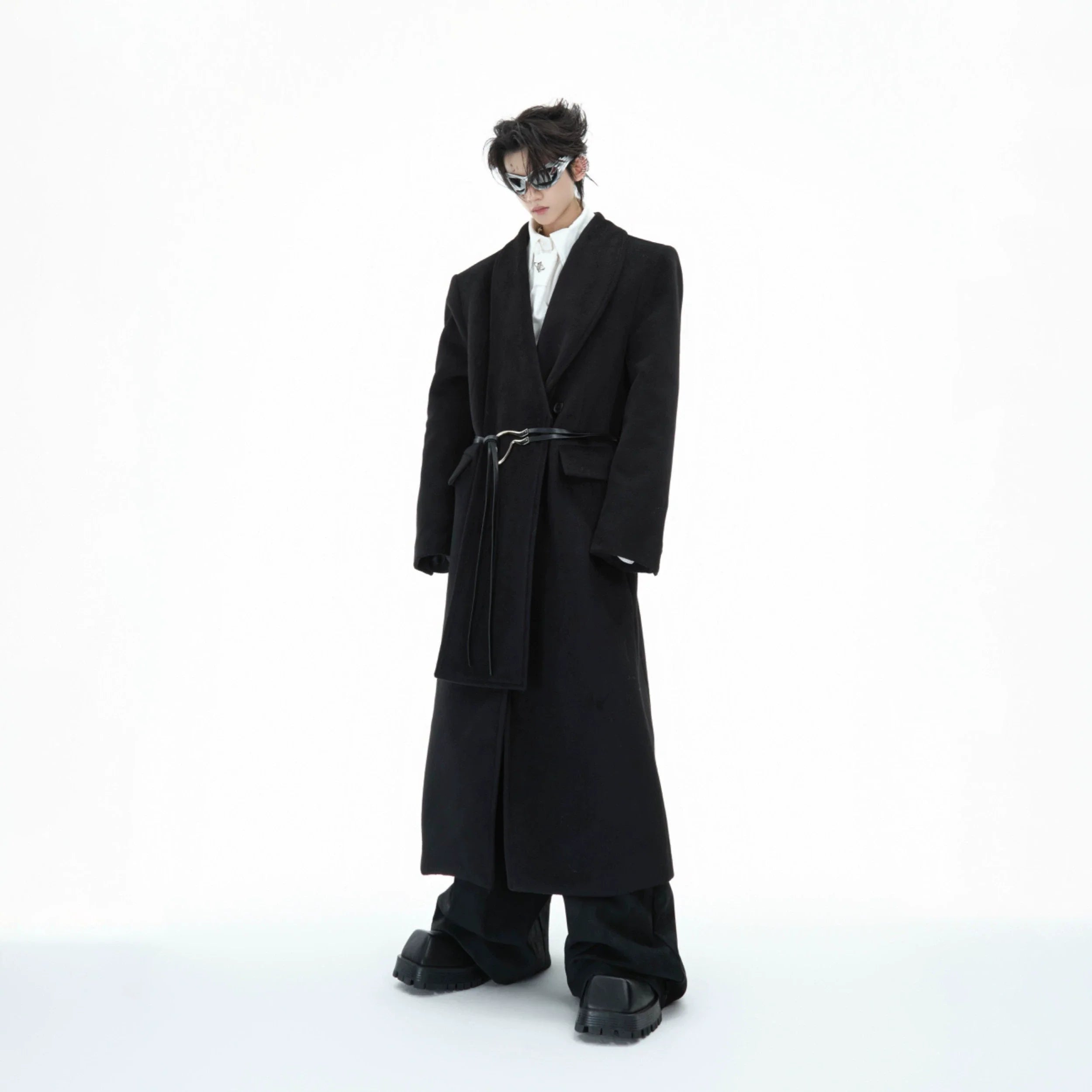Deconstructed wool trench coat with metal strap details, showcasing the oversized silhouette and leather accents