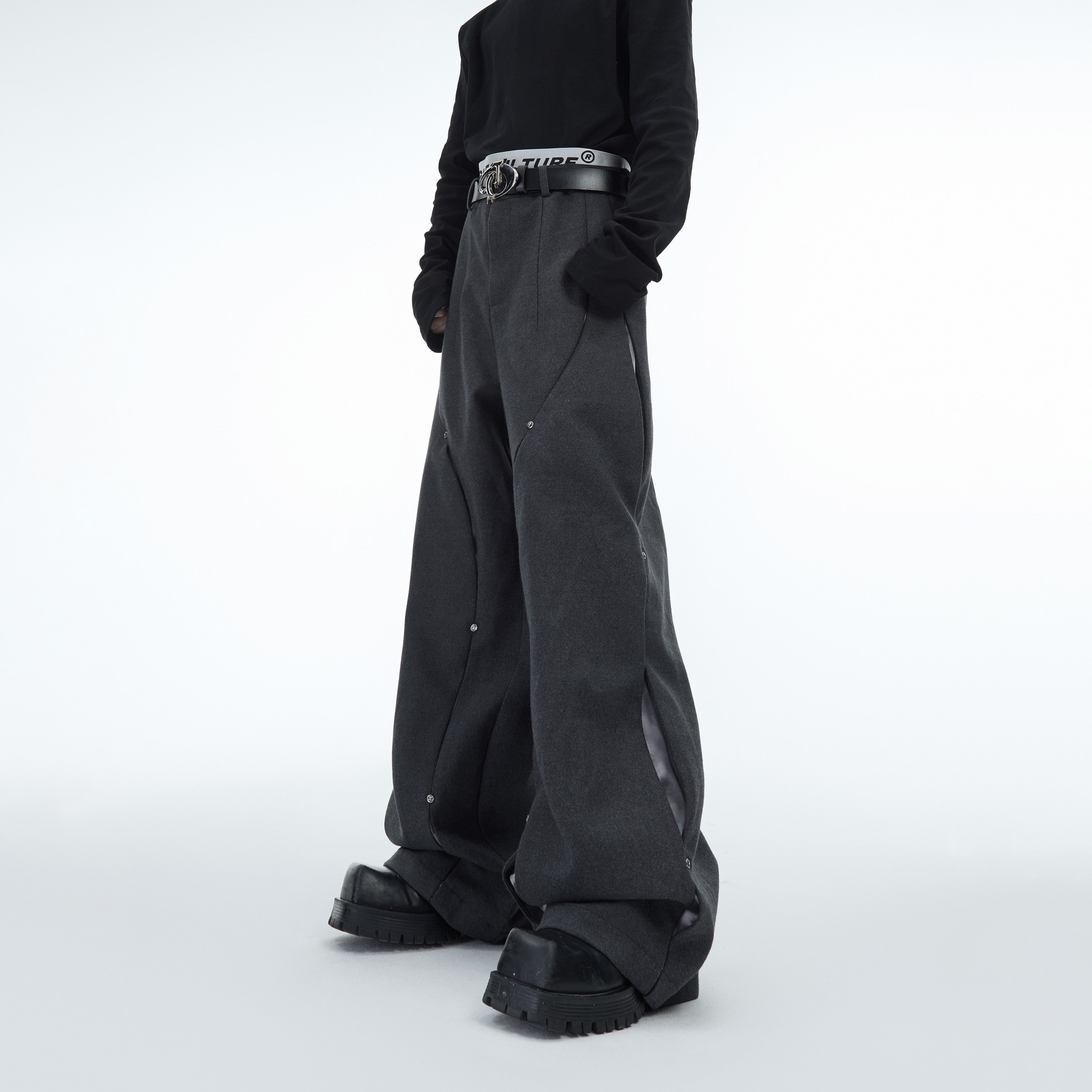 Side angle showing signature curved blade segmentation on these avant-garde wool trousers