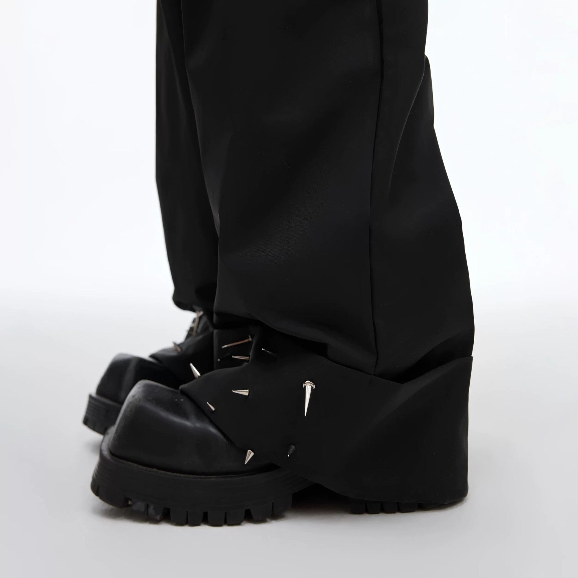 Side profile of yellow baggy trousers showing heavy drape and studs.