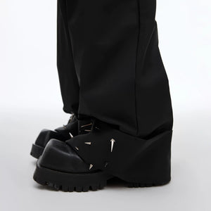 Side profile of yellow baggy trousers showing heavy drape and studs.