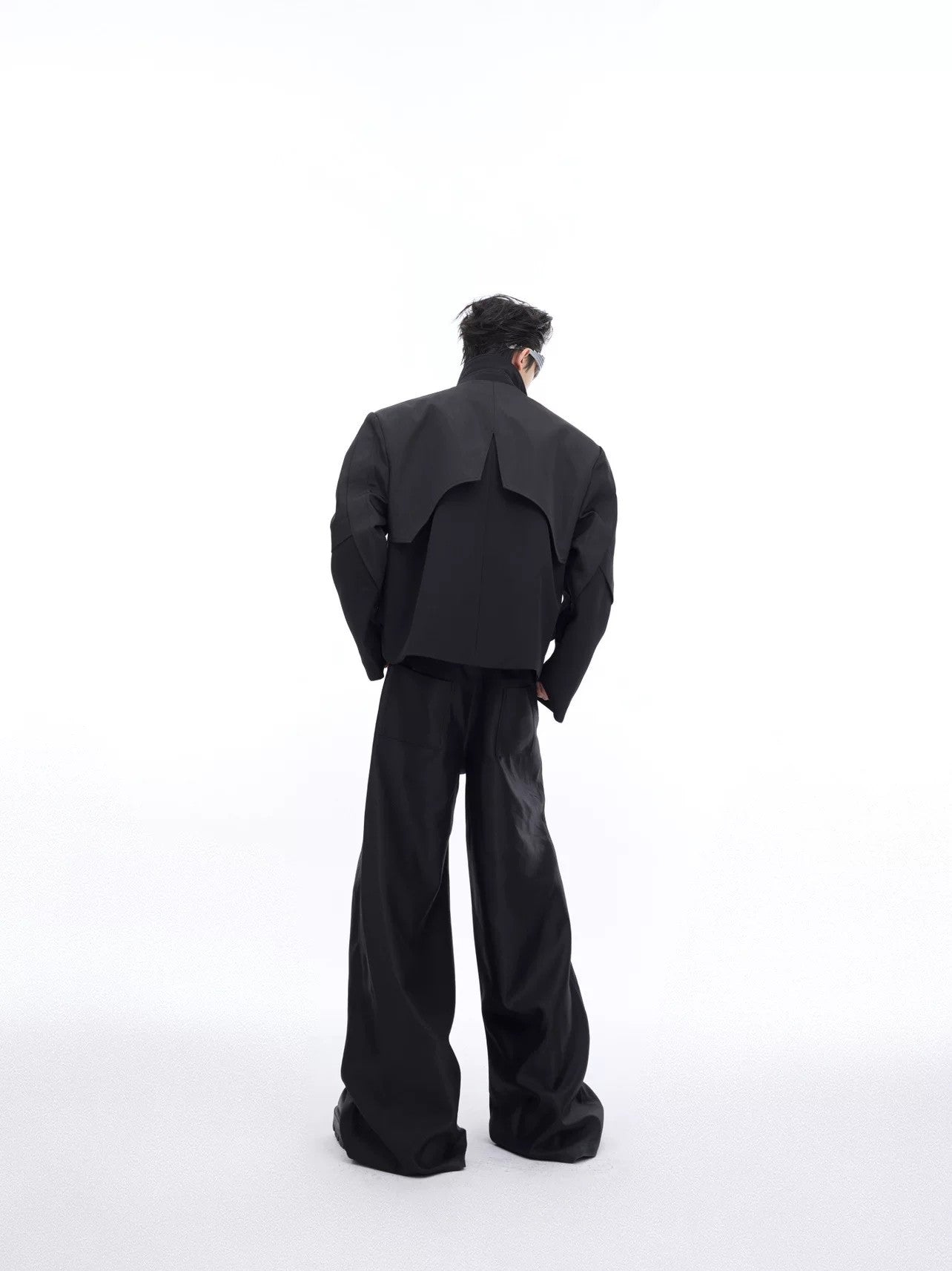 Model wearing a shiny black metallic jacket in an urban street setting