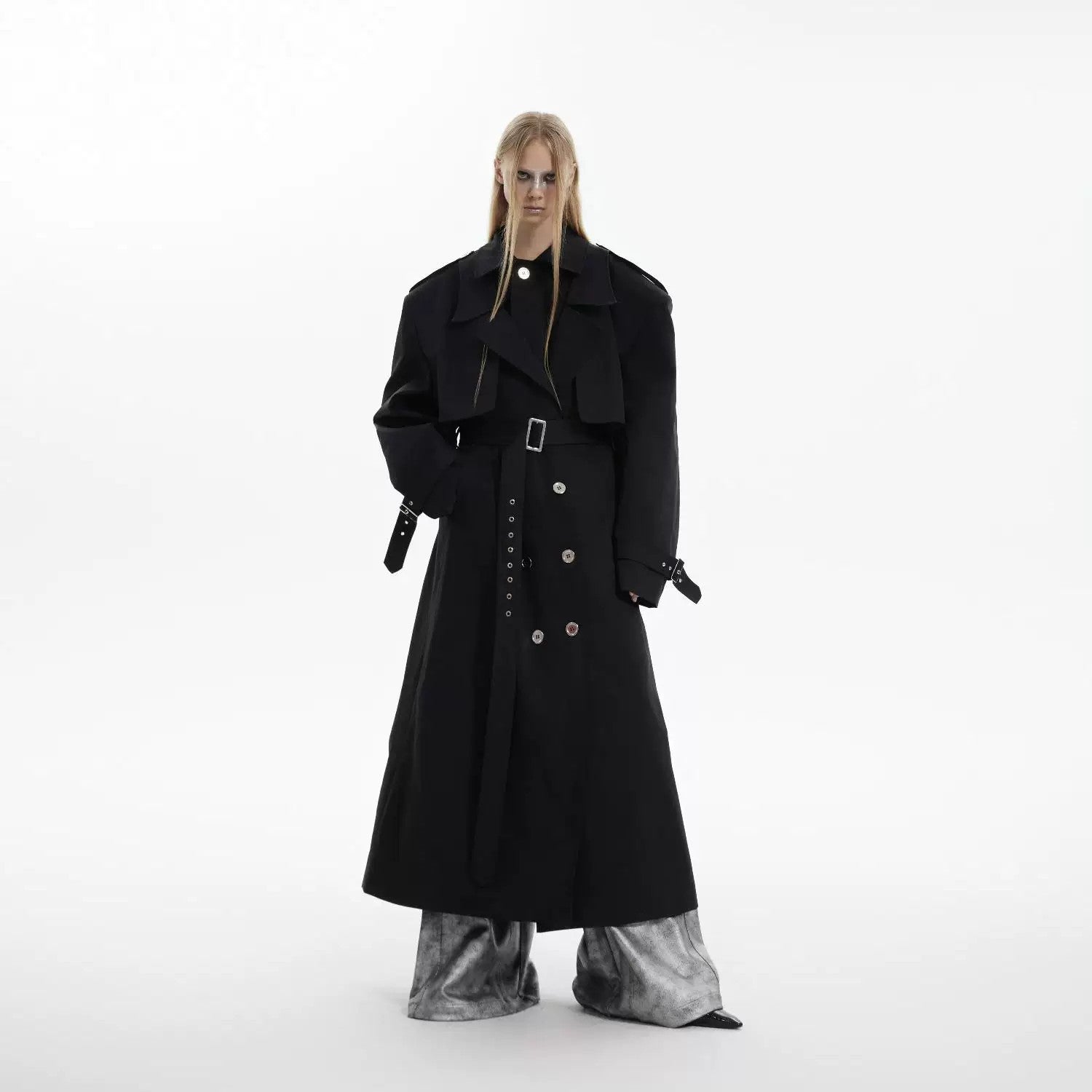 Model wearing a black oversized deconstructed trench coat with padded shoulders.