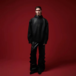 Model wearing a baggy black leather hoodie in a street setting