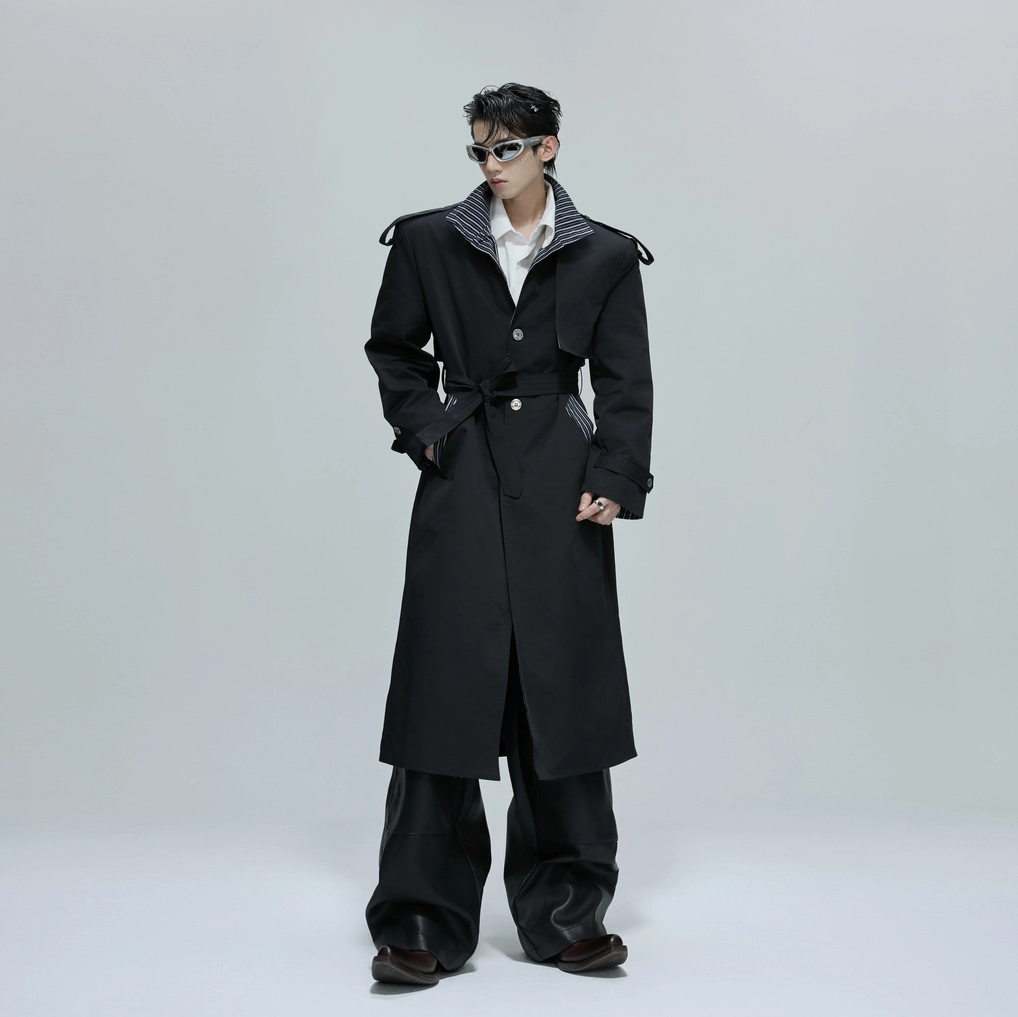 Front view of an oversized black stripe patchwork trench coat for streetwear style