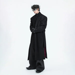 Front view of a black oversized wool overcoat with red diamond details