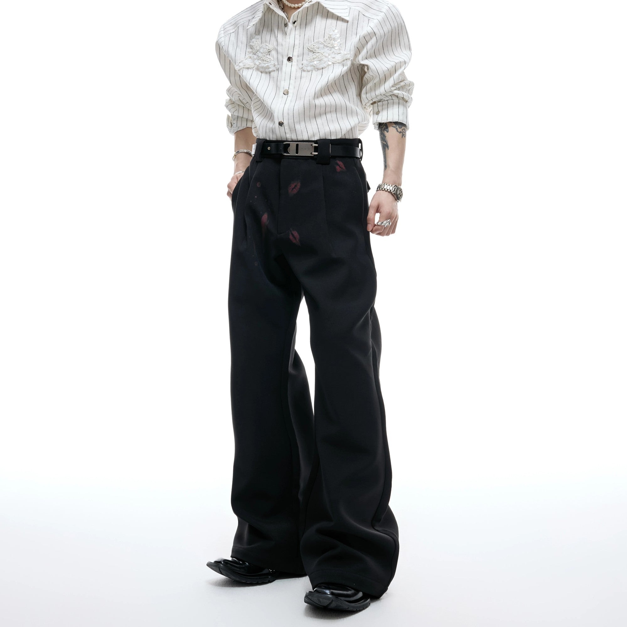 Front view of black pleated flare trousers with red lip graphic