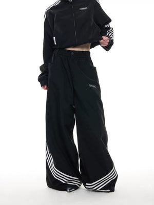 Side view of wide-leg baggy track pants with 4-stripe design