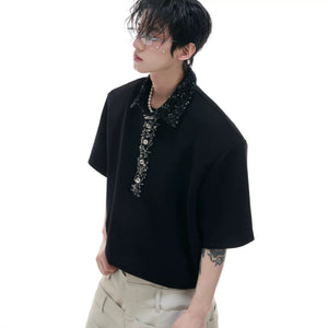 Men's black oversized polo shirt with sequin square neck and safety pin detail.