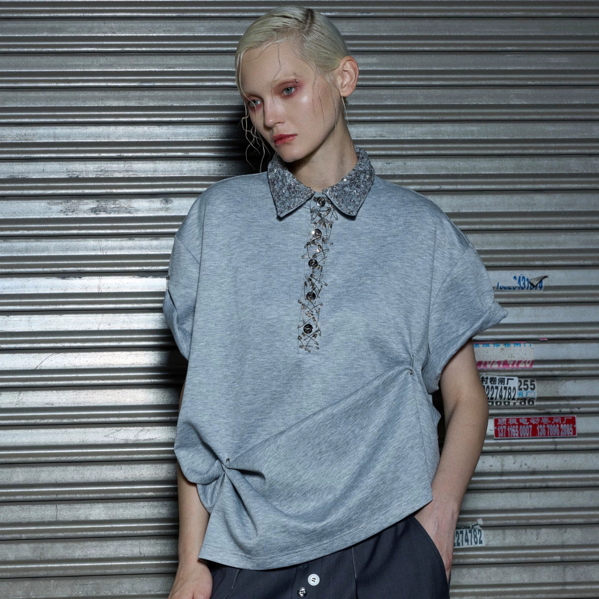Streetwear model wearing a gray sequin polo shirt with baggy pants.