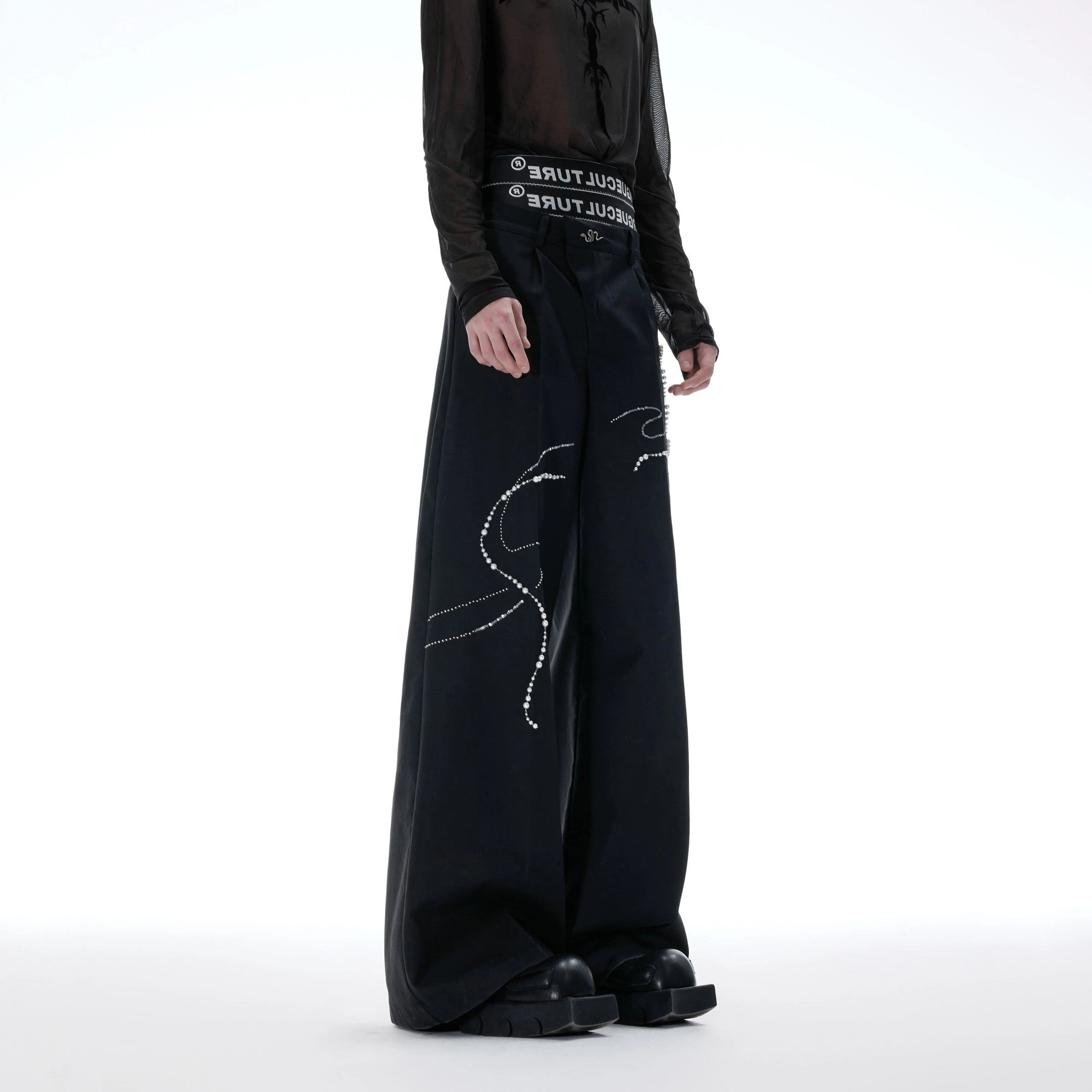 Close-up of luxury pearl-beaded snake design and metal hardware on trousers.