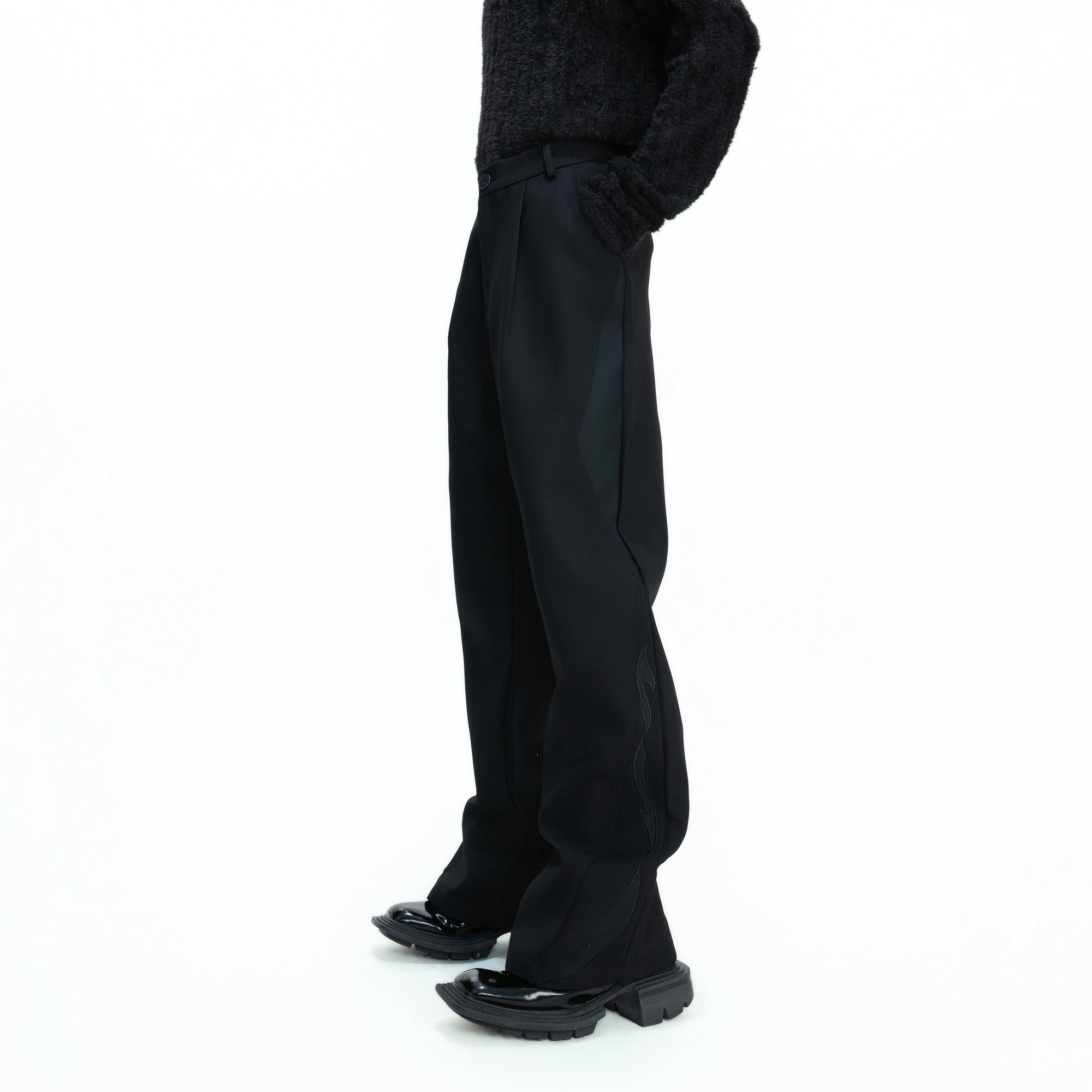 Front view of black deconstructed wide leg streetwear trousers with split cut design